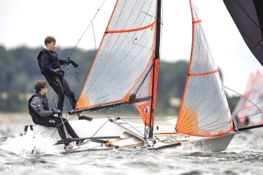 29er mit orange-weißem Gennaker bei viel Wind vor Schilksee, der Vorschoter steht im Trapez