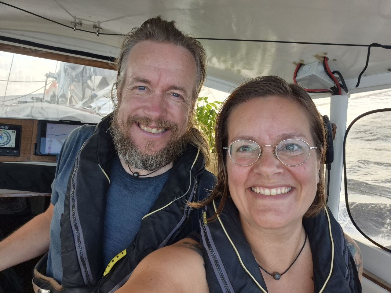 Henri und Susanna in Rettungswesten im Cockpit der Lille Ø unter dem Sprayhood, im Hintergrund das Plotterdisplay