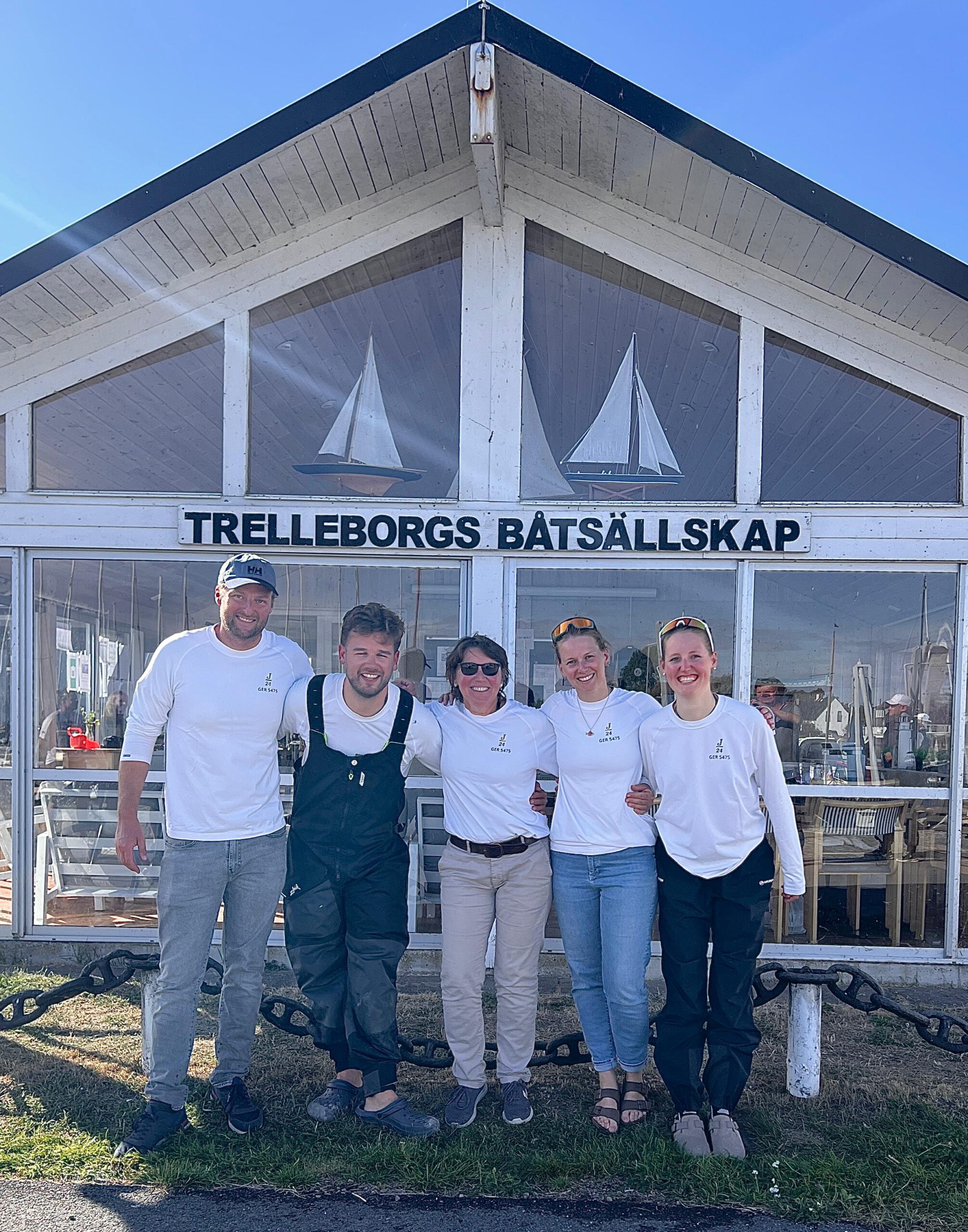 Die fünfköpfige High Jinks Crew in weißen Shirts vor dem Clubhaus der Trelleborgs Båtsällskap
